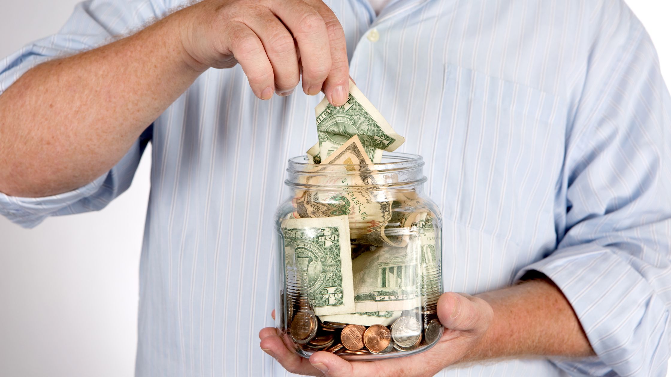 man in blue shirt putting cash in jar